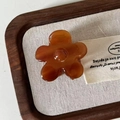 Amber acetate flower hair clip with resin finish placed on linen in vintage aesthetic style - Tortoise Flower