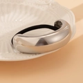 Primer plano de un coletero de metal plateado brillante en un plato de cerámica blanca - Estilo Minimalista en Forma de U / Plateado