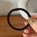 Close-up of black high-elastic hair tie with matte connector on hand-held display - Black