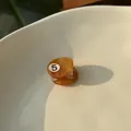 Detailed view of amber acetate mini hair claw clip with metallic spring in ceramic dish - Brown Billiard / Brown/No.5