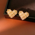 Vista macro de pendientes de corazón bañados en oro 18k con circonitas en joyero - Dorado