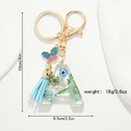 Detail of letter A resin keychain with blue dried flowers, butterfly and measurement specs - Letter A