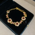 Macro shot of gold-plated floral bracelet with red gemstone in black jewelry box - Gold-Magenta