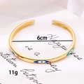 Detailed view of gold plated C-shaped evil eye cuff with 6cm diameter and 11g weight - Multicolor