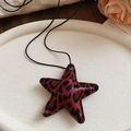 Gros plan détaillé du pendentif étoile léopard sur un plateau en céramique blanche - Collier-Rouge-Étoile