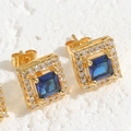 Macro detail of square blue zircon stud earrings with halo setting and gold plating - Sapphire Blue
