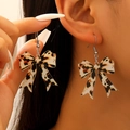 Detail of trendy leopard print acrylic bow earrings worn with silver hooks - Dark Brown Leopard Bow (05 White K 8829)
