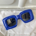 Close-up of blue glossy polygon cat eye sunglasses with dark lenses on fabric - Inflatable Square Royal Blue Glossy