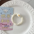 Détail d'un chouchou en satin crème avec un joli petit pendentif en forme d'ours - Triangle