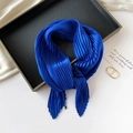 Detailed view of a pleated blue silk scarf elegantly knotted on a tray with sharp tips - 70*70cm / Pleated Royal Blue