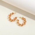 Orecchini a C dorati con texture a onde e strass rossi su uno sfondo minimalista chiaro - Rosso