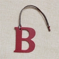 Detailed view of dark red leather letter B bag charm with visible texture and brown cord - Letter B Wine Red