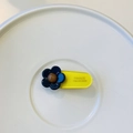Detail of France Handmade logo engraved on a yellow acrylic floral hair clip - Yellow Clip with Dark Blue Flower