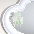 Detail of mint green marble acetate hair claw clip on heart-shaped mirror surface - Green and White