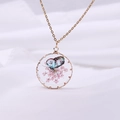 Macro view of a gold resin pendant featuring dried pink flowers and a colorful butterfly - Gold Pink