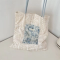 Detail of beige textured tote bag with blue floral lace patch and slender straps - Blue Lace + White Velvet