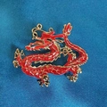 Detailansicht einer goldenen chinesischen Drachenbrosche mit roter Emaille und Schuppen - Totem Roter Drache