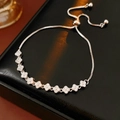 Detailed view of silver clover bracelet with sparkling zircons on black leather case - Silver Zirconia Four-Leaf Clover / Silver