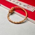 Bamboo-style sandalwood bracelet with Buddha pendant and beads over vintage red book - Sandalwood 5x7mm Bamboo Joint with Statue