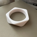 Detalle de un brazalete geométrico blanco de resina con exterior hexagonal e interior redondo - Blanco lechoso