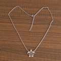 Macro-opname van een zilveren schildpad hanger ketting op hartvormige fijne schakels - Zeeschildpad / Zilver