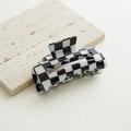 Classic black and white checkered hair claw clip displayed on a textured stone surface - Hollow Black White