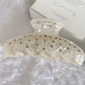 Dettaglio ravvicinato di una pinza per capelli in acetato bianco perla con strass lucidi - Bianco