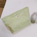 Detailansicht der hellgrünen Jacquard-Kosmetiktasche mit floraler Textur und Stoffetikett - Hellgrüne Geprägte Große Blüte