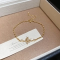 Dettaglio del bracciale a farfalla in oro 18k con zirconi bianchi su portagioie in pelle - Bracciale Oro