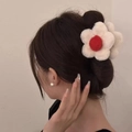 Plush white flower hair claw with red center shown on woman's updo hairstyle - Off-white