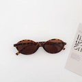 Oval tortoiseshell sunglasses with dark brown lenses on a minimalist grey background - Leopard Print