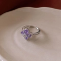 Nahaufnahme eines Kleeblatt-Rings mit lila Zirkon-Steinen auf Vintage-Keramik - Silber/Lila