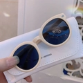 Close-up of stylish round beige kids sunglasses with a white textured protective pouch - Beige Frame Grey Lens