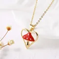 Macro detail of gold heart pendant necklace featuring a red and white enamel mushroom - Heart Outline Mushroom