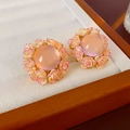 Détail de boucles d'oreilles fleurs roses élégantes avec pierre centrale sur velours blanc - Rose