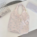Close-up of pink fabric tote bag featuring blue cat floral prints and white woven label - Printed Cat Pink