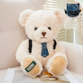 Cream teddy bear plush with blue floral tie and black backpack on a soft white sofa - Off White / 21cm