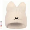 Detailaufnahme der beige Strickmütze mit Katzenohren und schwarzer Katzenstickerei - Gebrochenes Weiß