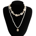 Detail of layered beach style necklace featuring white sea shells, starfish, and turtle pendant - Gold