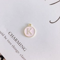 Detailed view of round pink enamel pendant with gold metal letter K for jewelry making - Letter K