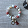 Macro detail of pumpkin silicone beaded keychain with red leather tassel and gold ring - Tan