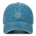 Close-up of white 'GOOD VIBES' embroidery and skull gesture on washed blue baseball cap - One Size / Lake Blue