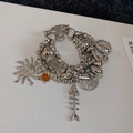 Detailaufnahme der mehrlagigen silbernen Perlenarmband mit Sonnen- und Muschelanhängern - Silber