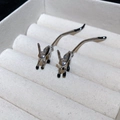 Nahaufnahme von hasenförmigen Silbernadel-Ohrringen mit Emaille-Details auf einem Schmucktablett - Silberfuchs
