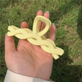 Matte pale yellow wave hair claw clip held by hand against a natural green lawn backdrop - Matte Twist Yellow-11cm