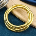 Detailed macro view of flexible golden snake-bone layered bracelet with metallic luster - Gold