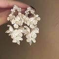 Detalle de pendientes de flor de nácar con cristales brillantes y acabados dorados - Pin de Plata - Blanco (HE15735)