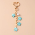Detail of a gold keychain featuring blue enamel flowers and a white pearl bead decoration - Heart Ring / Blue