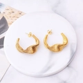 Elegant gold twisted wire hoop earrings displayed on a marble plate in a creative style - Irregular Twisted Arc