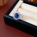 Nahaufnahme eines königsblauen Zirkonrings mit silberner Diamantfassung in einer Box - Offener Ring - Silber / Blaue Blume